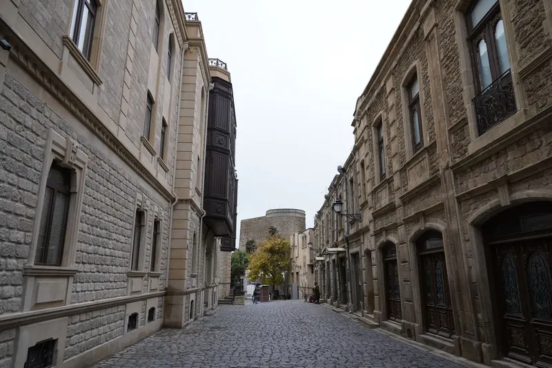 Cobblestone street in Baku's Old City with stone buildings and the Maiden Tower, Azerbaijan