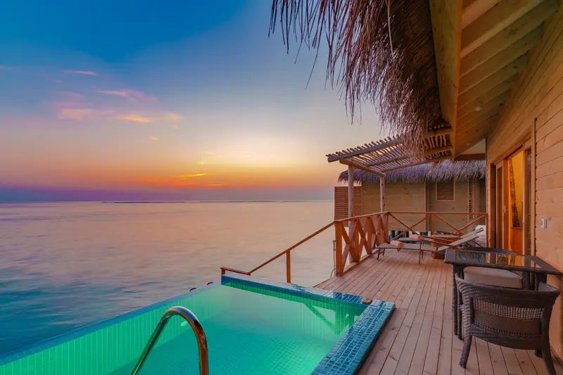 Overwater villa deck with a private pool at sunset in the Maldives