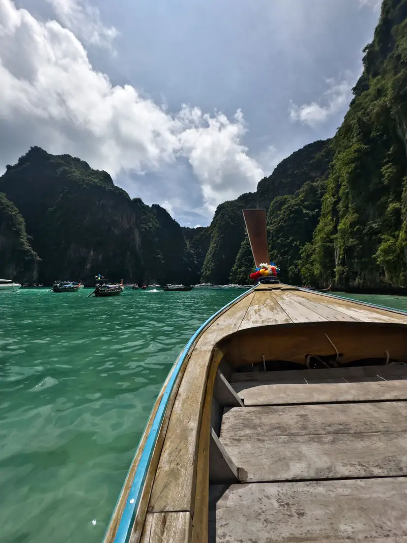 A longtail boat on turquoise water between the cliffs of the Phi Phi Islands, Thailand